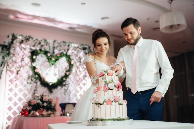 Newlyweds happily cut, laugh and taste the wedding cake