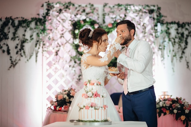 Newlyweds happily cut, laugh and taste the wedding cake