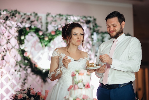 Newlyweds happily cut, laugh and taste the wedding cake