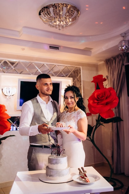 Newlyweds happily cut, laugh and taste the wedding cake