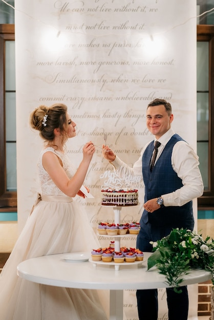 Newlyweds happily cut, laugh and taste the wedding cake