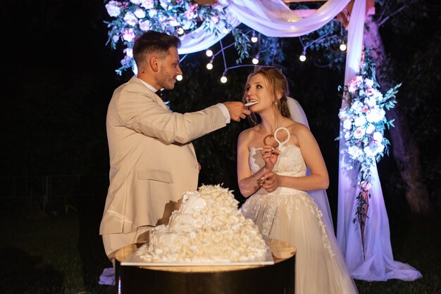 Newlyweds happily cut, laugh and taste the wedding cake