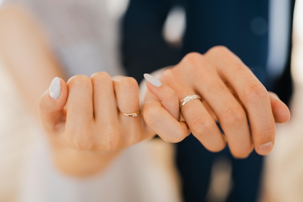 Newlyweds hold hands hold hands together with little fingers\
holding hands together in the foreground closeup