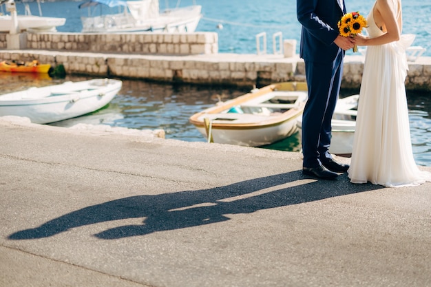 Foto sposi novelli si tengono per mano sul mare coppia che si tiene per mano matrimonio