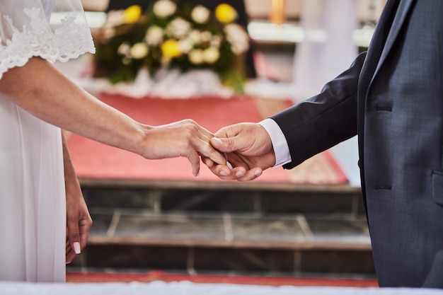 Newlyweds hold hands during a wedding in a catholic church