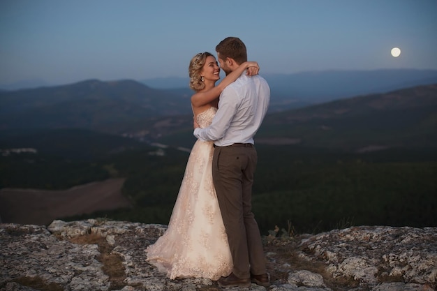 Newlyweds hug at night in the mountains