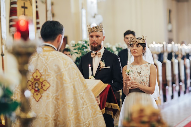 Фото Молодожены в церкви. священник празднует свадебную мессу в церкви