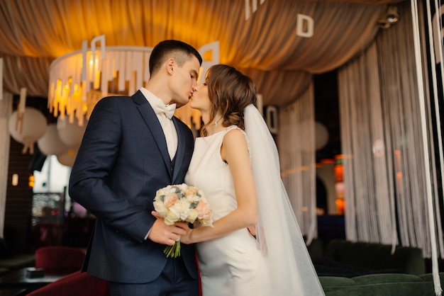 Newlyweds kiss while holding a bouquet. Wedding, love, relationship concept.