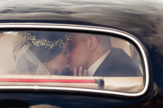 Newlyweds kissing in the car the newlyweds are visible through\
the window