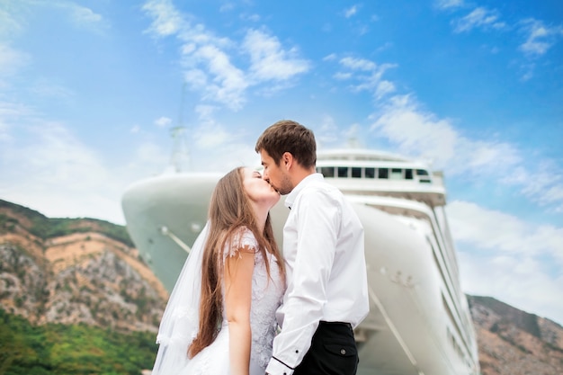 Newlyweds in love kissing near big cruise ship