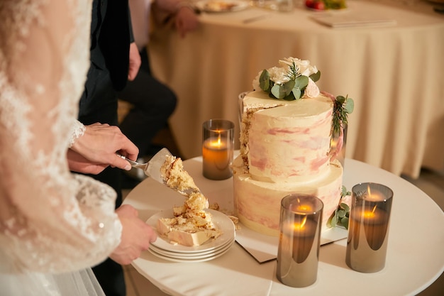 신혼 부부는 접시에 웨딩 케이크의 첫 번째 조각을 놓습니다.