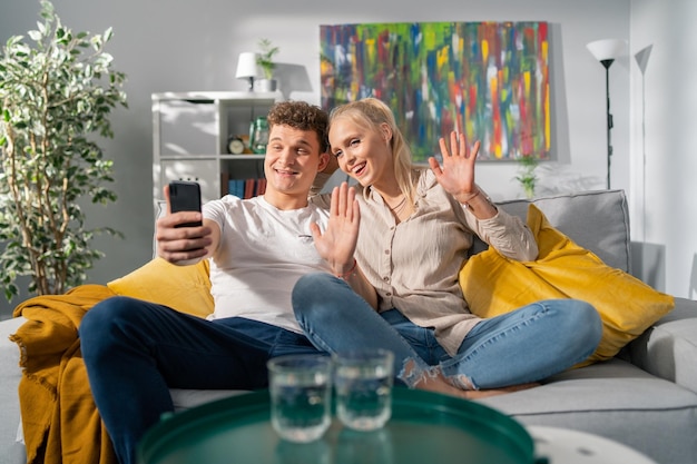 The newlyweds sit on couch in their new apartment relaxing after move calling their parents