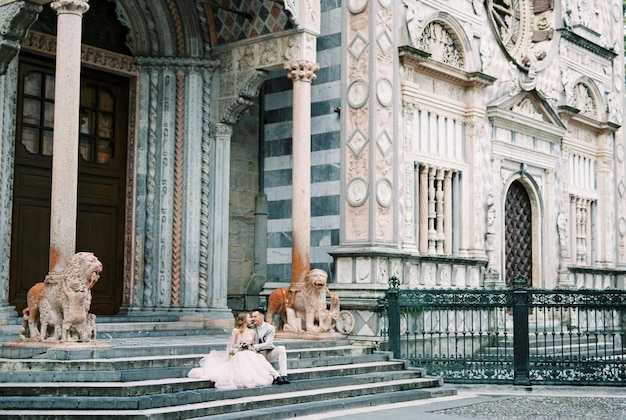 Newlyweds sit on the steps of the church in front of the entrance bergamo italy