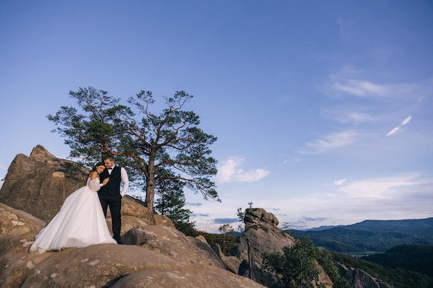 The newlyweds stand on a rock hugging enjoying the beautiful naturewedding concept outdoors