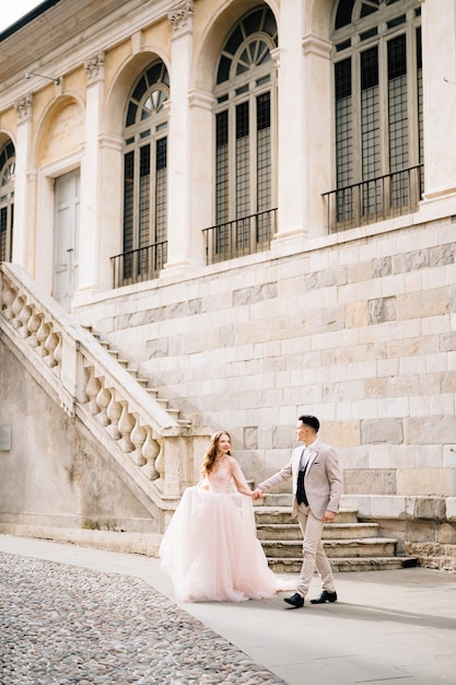 Newlyweds walk from the steps of an old building in bergamo italy