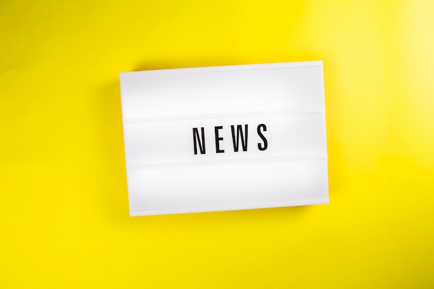 News word on lightbox on yellow background isolated top view flat lay