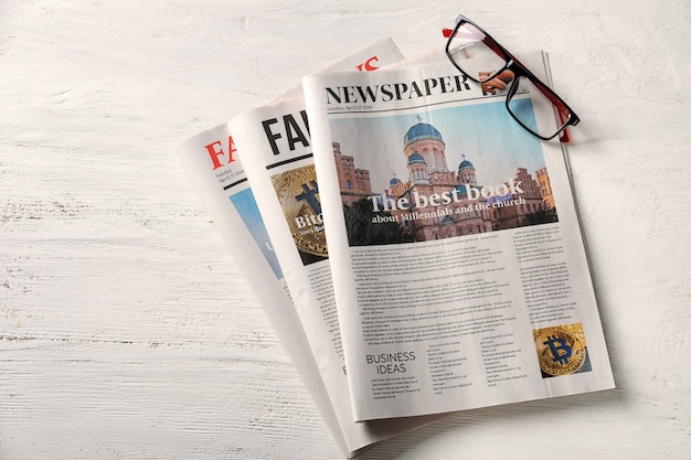 Newspapers and glasses on white wooden table