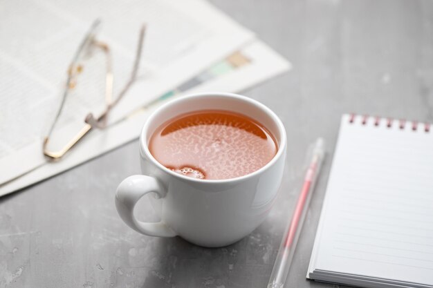 Newspapers and white tea cup with reading glasses