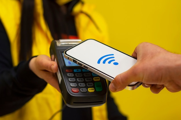 NFC technology. A male buyer holds a smartphone with wireless payment in his hands