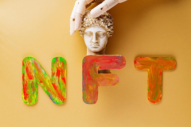 Photo nft non-fungible token . artificial fingers hug the plaster head of hermes. nft inscription on a beige background. creative nft art concept