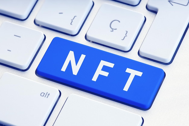 Текст NFT или Non Fungible Token на синей клавише клавиатуры компьютера