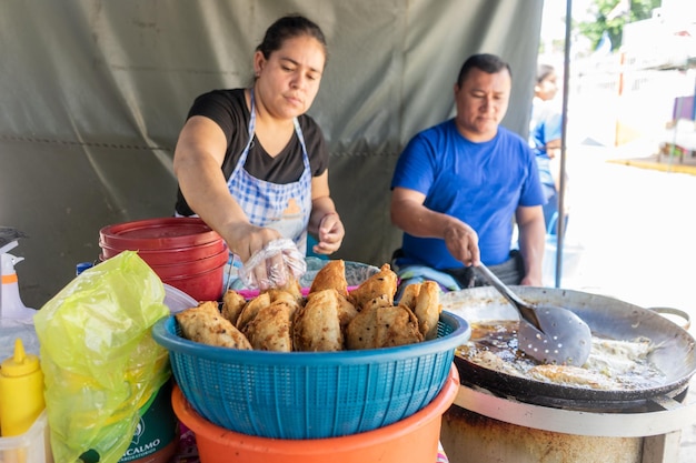 Foto uomo e donna nicaraguense che cucinano enchiladas un tipo di cibo di strada