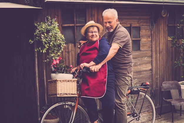 nice adult caucasian two man and woman couple laugh and have fun together on a bike in the garden at home. natural happy lifestyle for a togetherness life after the works at the office