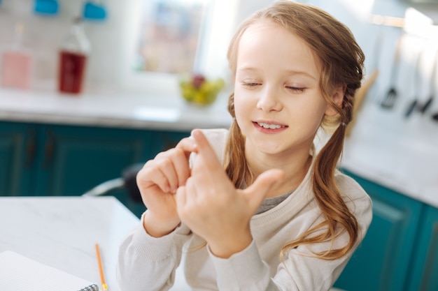 Nice alert blond girl smiling and looking at her hands while counting on her fingers