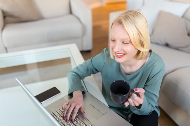 Foto bella bella signora lavorare al notebook sedersi sul divano a casa controllare su negozi online per cyber monday tecnologia di vendita concetto donna per ufficio alternativo freelance