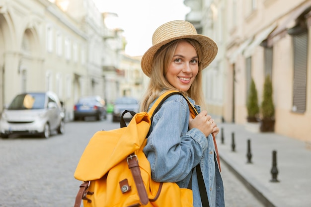 Nice beautiful millennial tourist woman with backpack in jeans jacket  discover European city at holiday travel.