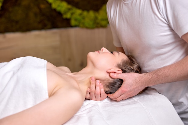 Nice beautiful woman lying on massage table and enjoying massage by professional