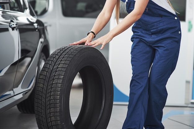 La bella riparatrice bionda sta facendo il suo lavoro. all'interno al negozio di auto