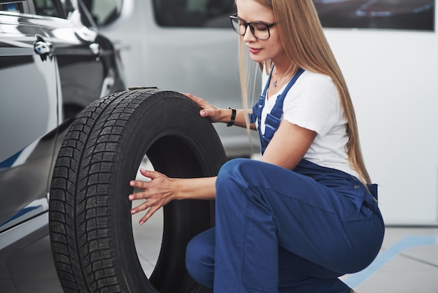 La bella riparatrice bionda sta facendo il suo lavoro. all'interno al negozio di auto