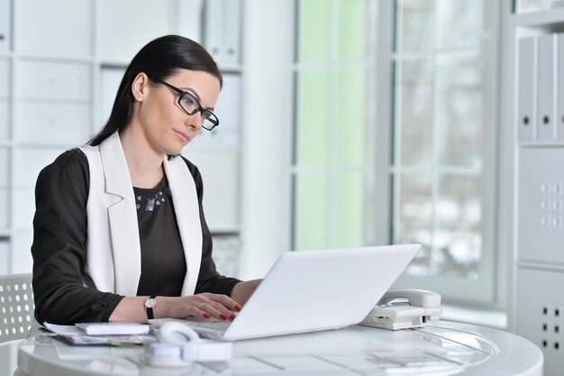 Nice business woman sitting at table with laptop