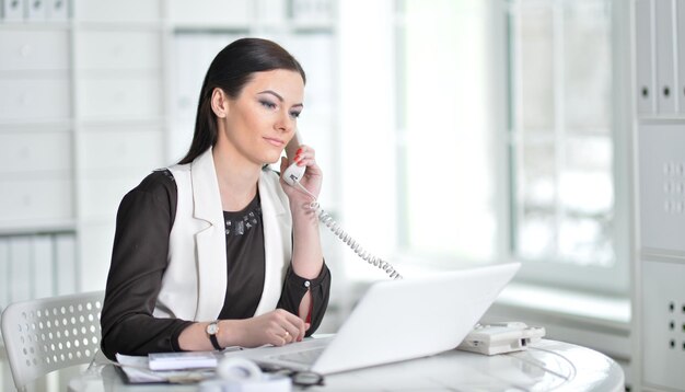 Nice business woman sitting at table with laptop