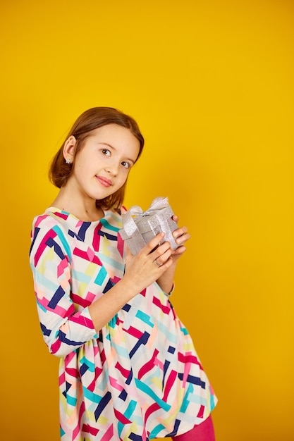 Nice child teenage girl hold silver present box in a hand in the studio