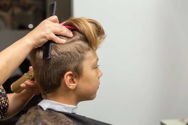 Nice european boy getting hairstyle in barbershop