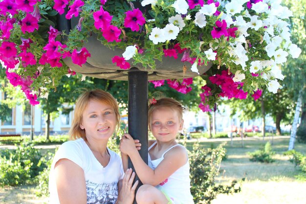 nice family mother and her daughter and many flowers in city park