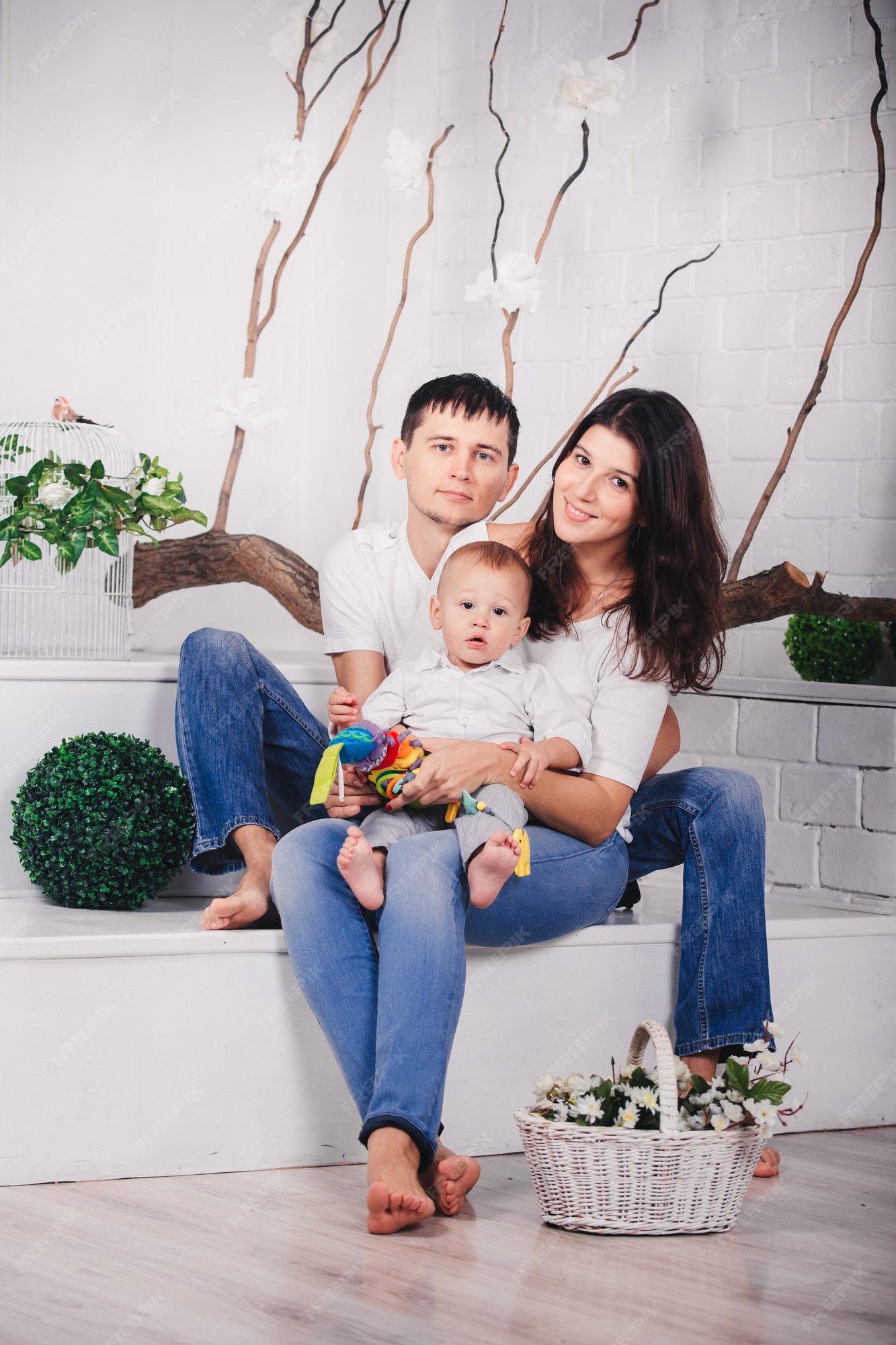Premium Photo | Nice family in studio background in light modern interior  indoors. smiling young mother and father with child son posing together and  sitting on sofa.