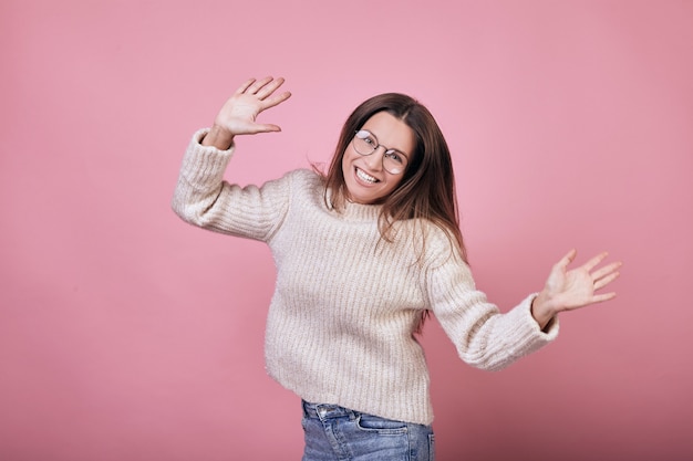 Nice funny girl in sweater and glasses jumping and smiling