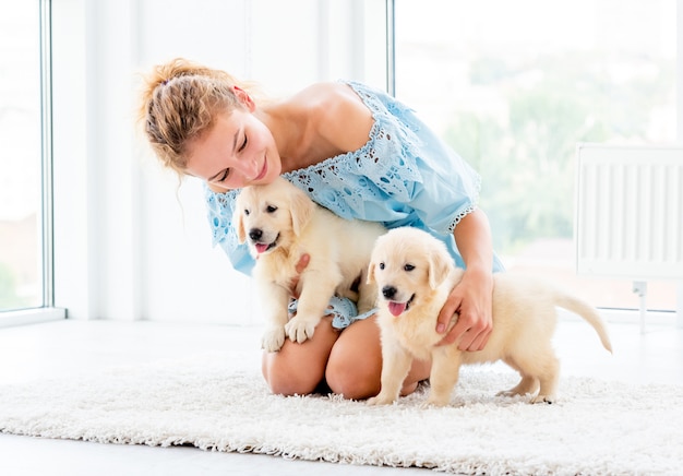 Nice girl hugging retriever puppies