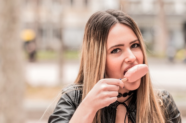 Bella ragazza sta camminando per le strade della città e sta mangiando un gelato