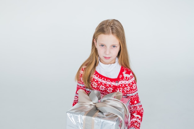 Bella ragazza con regalo di natale. ragazzo carino, bambino indossa un regalo di holding maglione nordico lavorato a maglia rosso