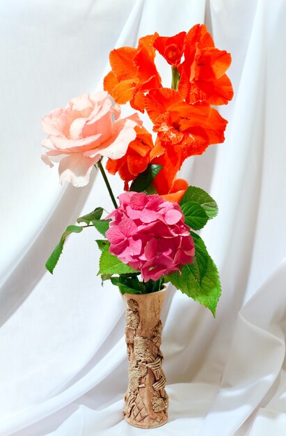 Nice gladiolus, hydrangea and rose summer bouquet on white cloth background