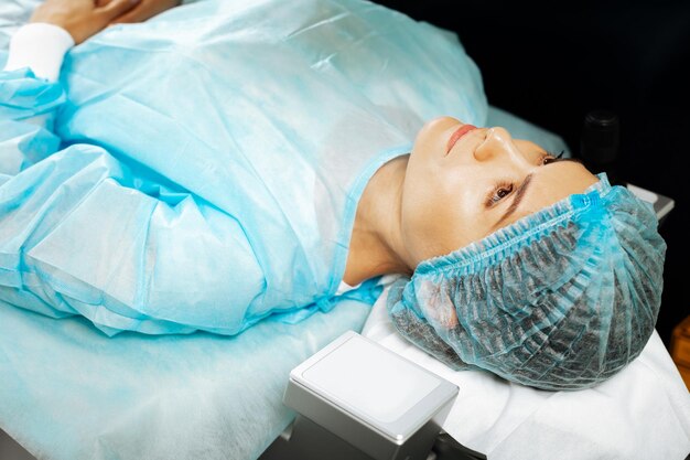 Nice good looking woman lying on the medical bed before having an operation on her eyes