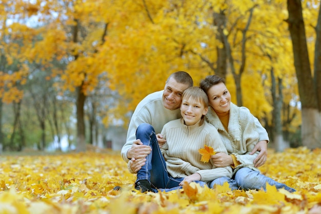 Милая счастливая семья, сидя в осеннем парке