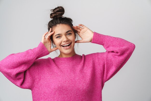 nice joyful woman in pink sweater smiling and grabbing her head isolated over white wall