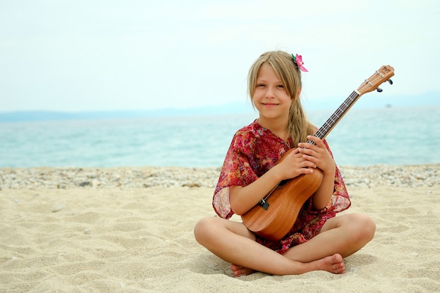 Nice little girl on the beach with ukulele