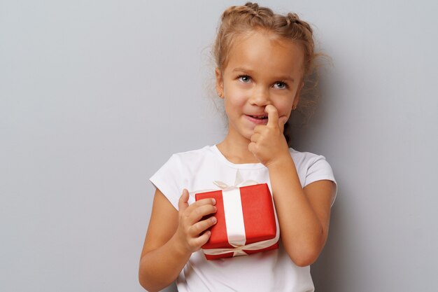 Nice little girl holding a red gift box in her hands