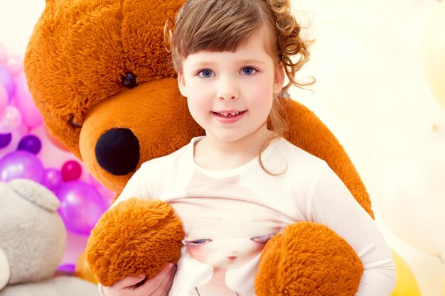 Nice little girl posing in arms of big teddy bear